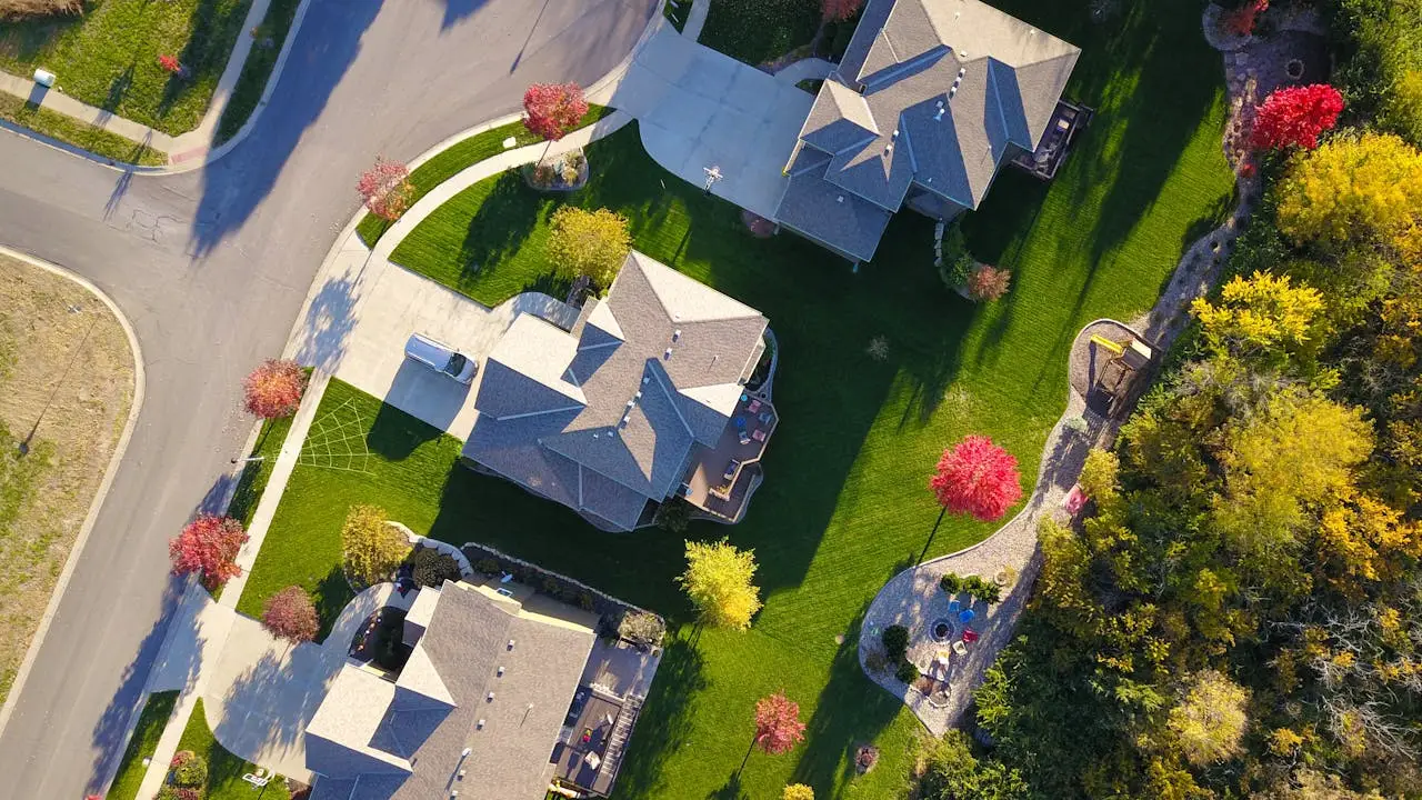 why-choose-us A picturesque aerial view showcasing suburban homes with vibrant gardens and tree-lined streets.