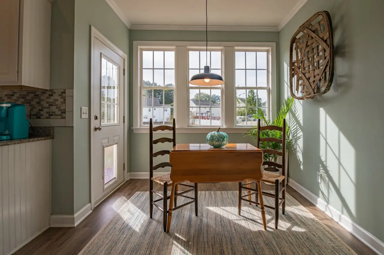our-services-1 Bright dining area with wooden furniture and large windows showcasing natural light.